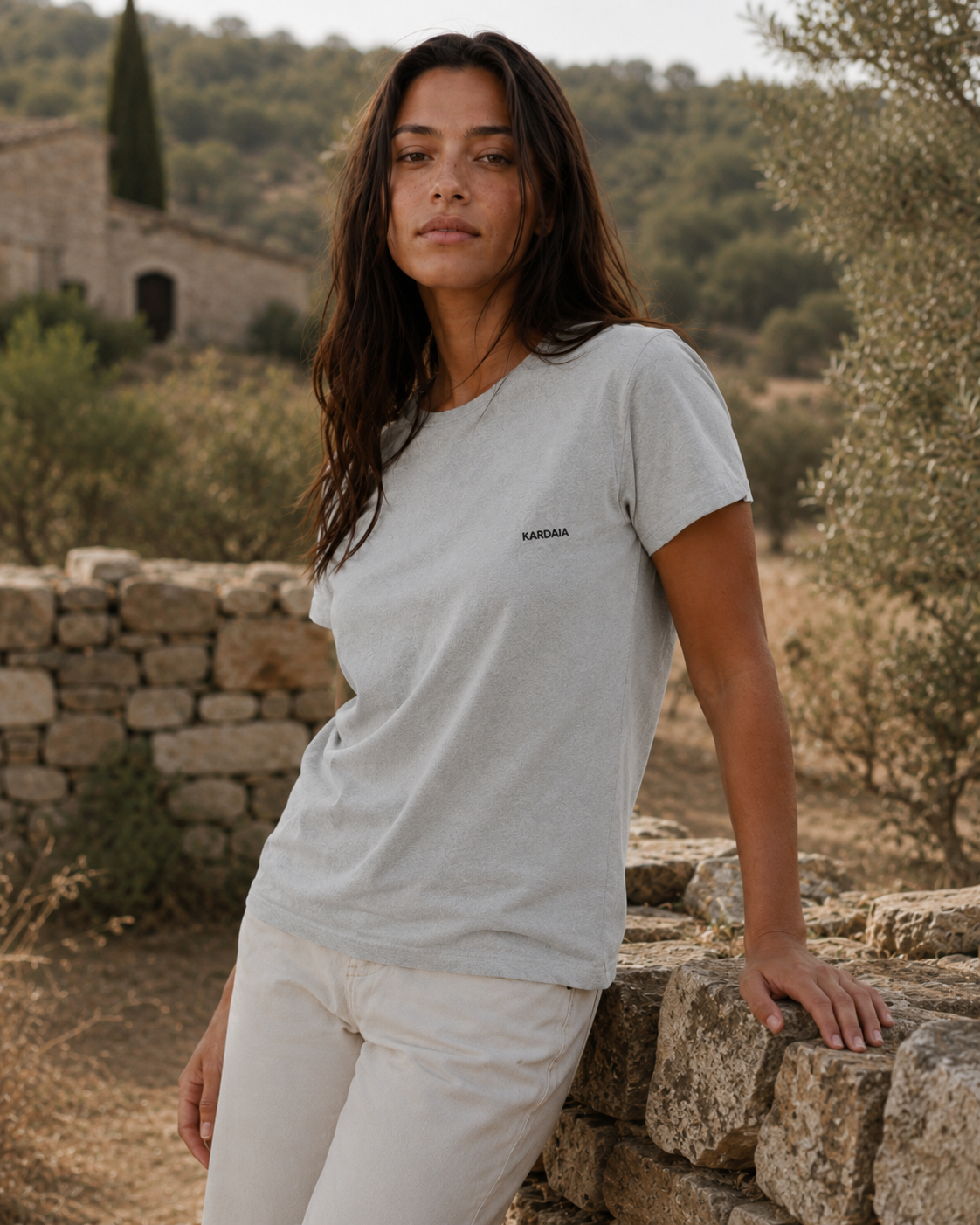Femme appuyé sur un mur qui porte un t-shirt recyclée Kardaia gris
