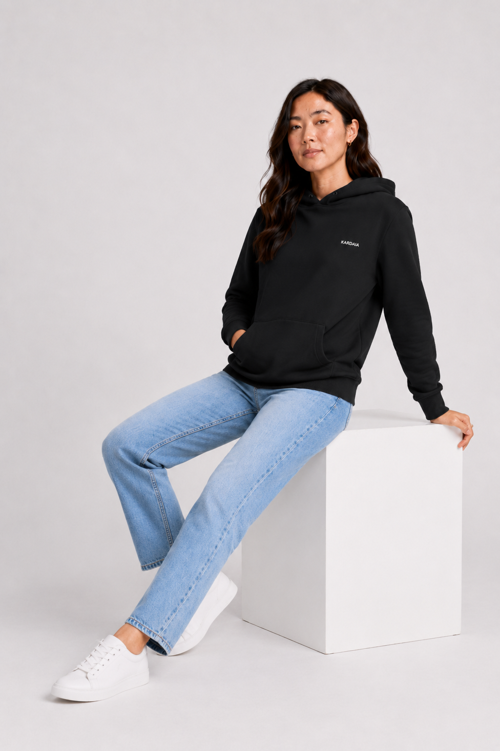 Sweat à capuche noir pour femme en coton biologique avec poche kangourou, porté avec un jean