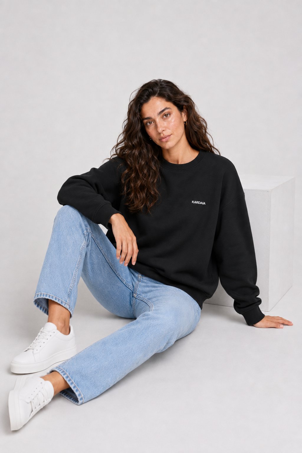 Femme portant un pull oversize noir en coton biologique avec un jean bleu clair