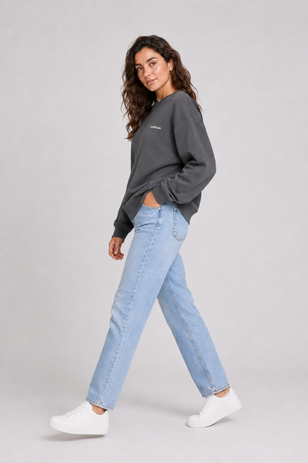 Femme portant un pull oversize gris charbon en coton biologique avec un jean bleu
