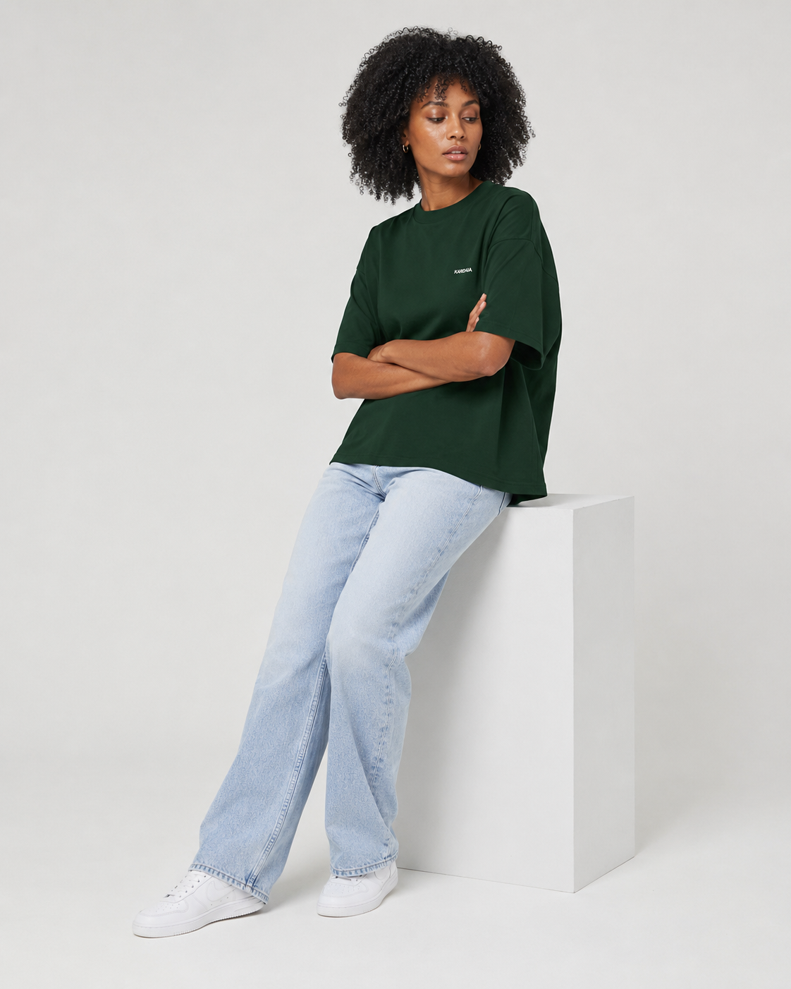 Femme portant un t-shirt oversize vert foncé en coton biologique avec un jean bleu clair