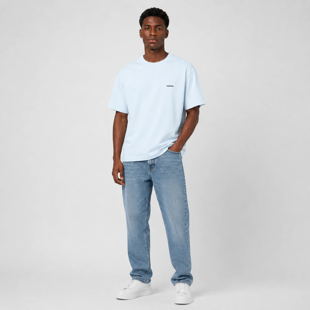 T-shirt homme Kardaia bleu ciel en coton biologique, photographié de face avec un jean droit. Sa coupe classique, ses manches courtes et sa teinte pastel composent une silhouette simple et décontractée.