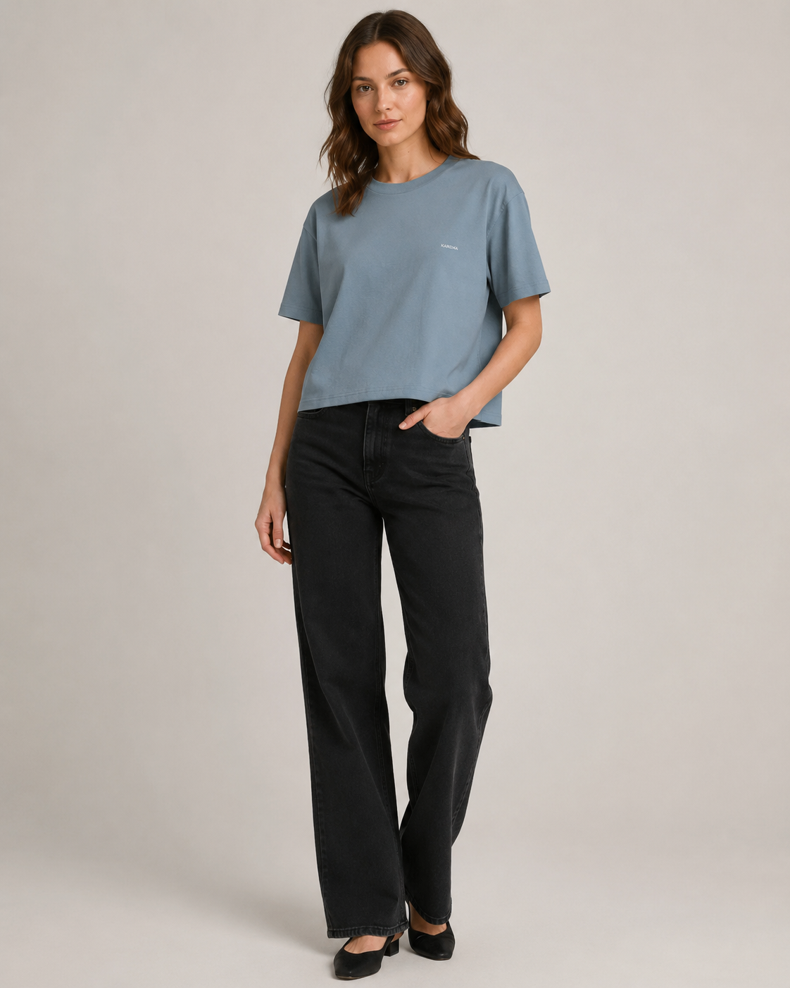 Femme portant un t-shirt boxy bleu pierre en coton biologique avec un jean noir