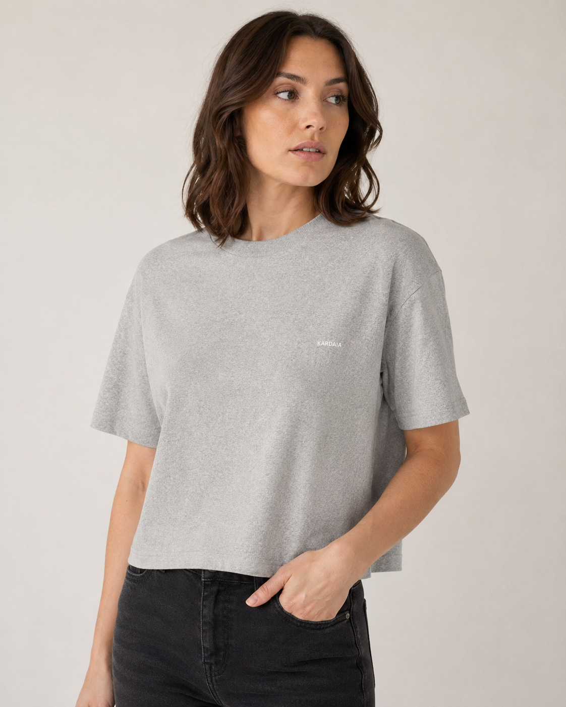 Gros plan sur un t-shirt boxy femme gris chiné en coton biologique porté avec un jean noir