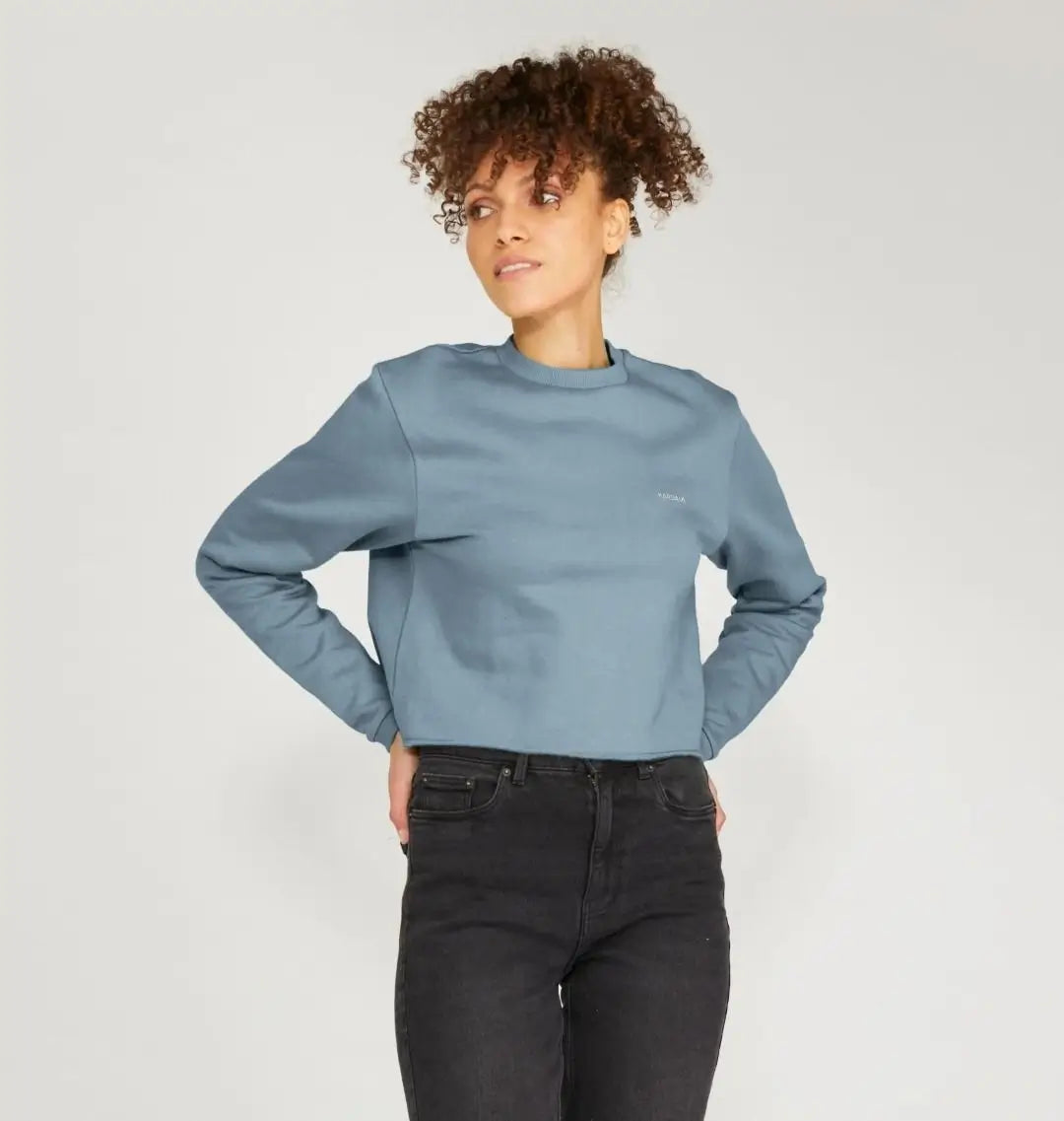 Femme portant un pull boxy bleu horizon coupe ample, avec jean noir taille haute.