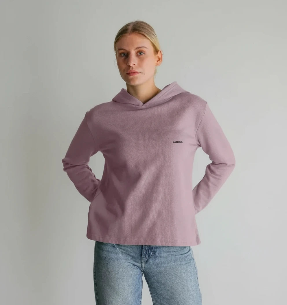 femme portant un sweat à capuche coupe décontractée couleur mauve poudré avec un jean clair