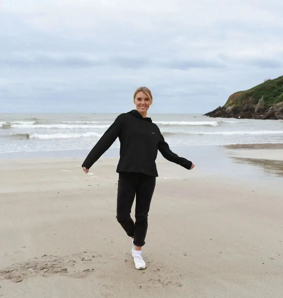 femme en sweat noir basalte recréé KARDAIA marchant au bord de la mer