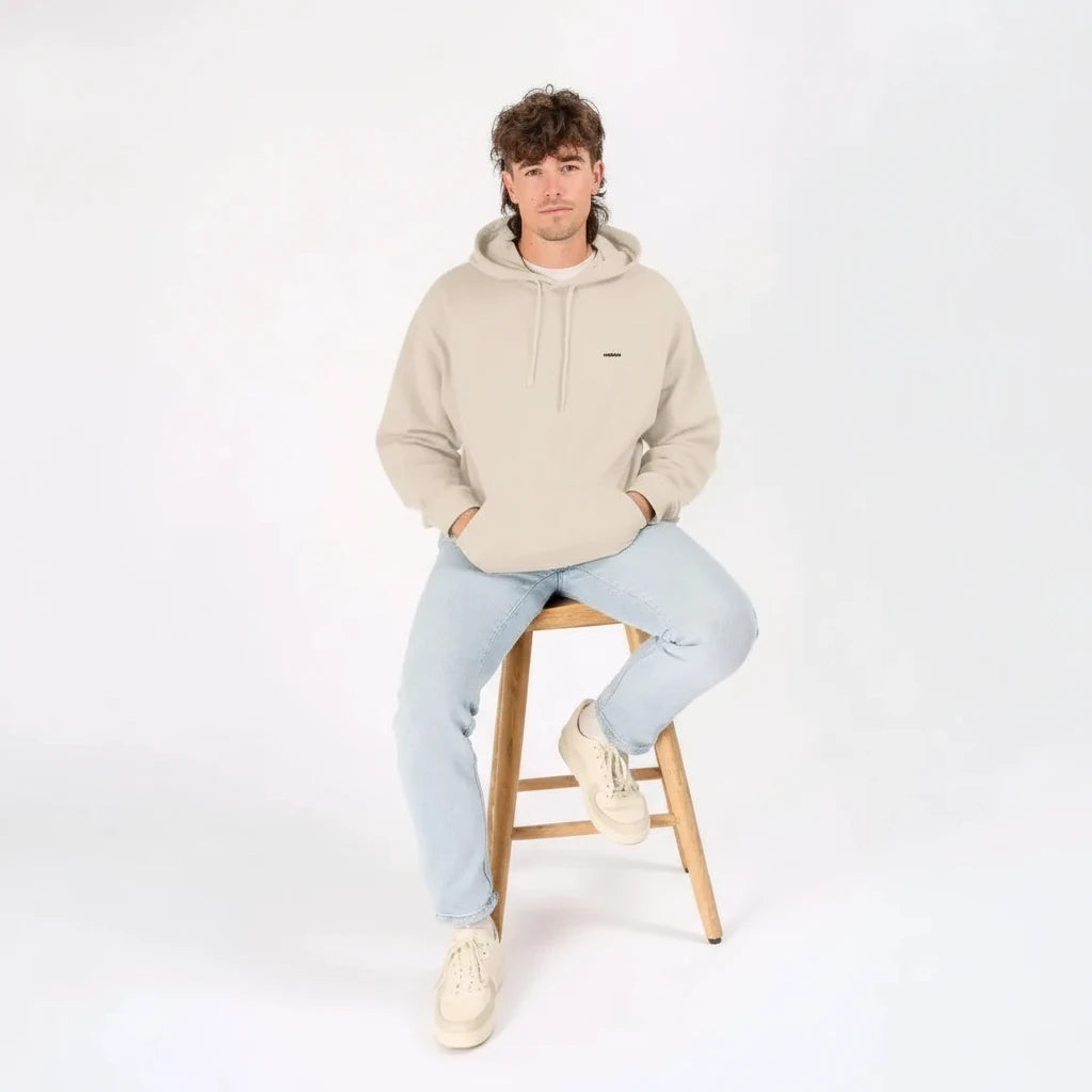 Homme assis portant un sweat à capuche KARDAIA avoine avec un jean clair