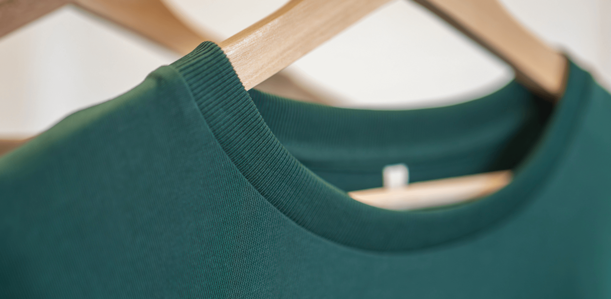 Gros plan sur le col d’un sweat vert en coton bio, finition soignée et texture douce