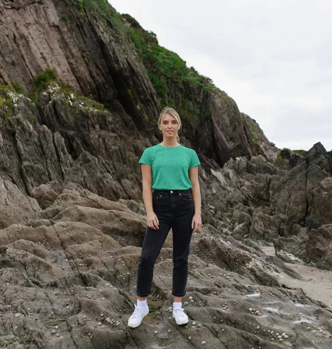 femme portant un t-shirt vert océan KARDAIA sur les rochers, style naturel et responsable