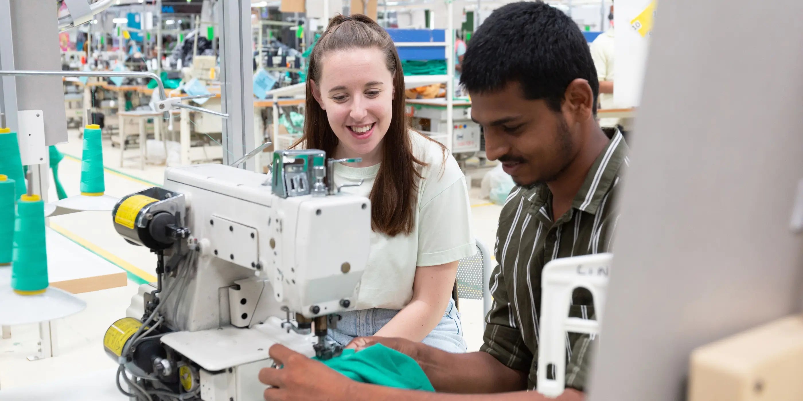 Collaboration entre couturière et couturier sur une machine à coudre, dans un atelier textile éthique