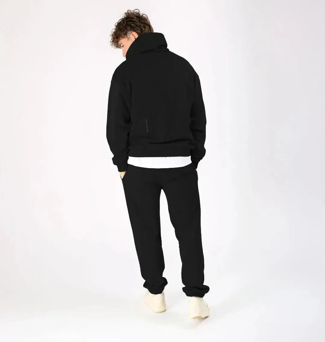 Homme de dos en hoodie noir KARDAIA, associé à un pantalon de jogging noir, posture décontractée