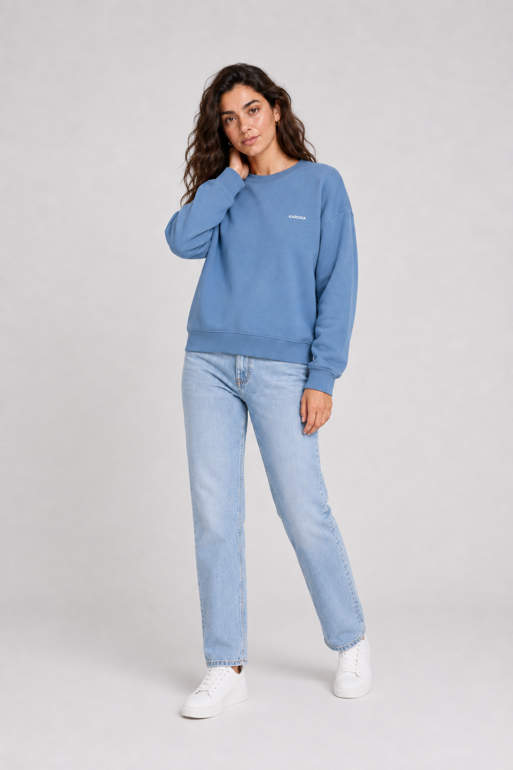 Femme portant un pull oversize bleu en coton biologique avec un jean bleu clair