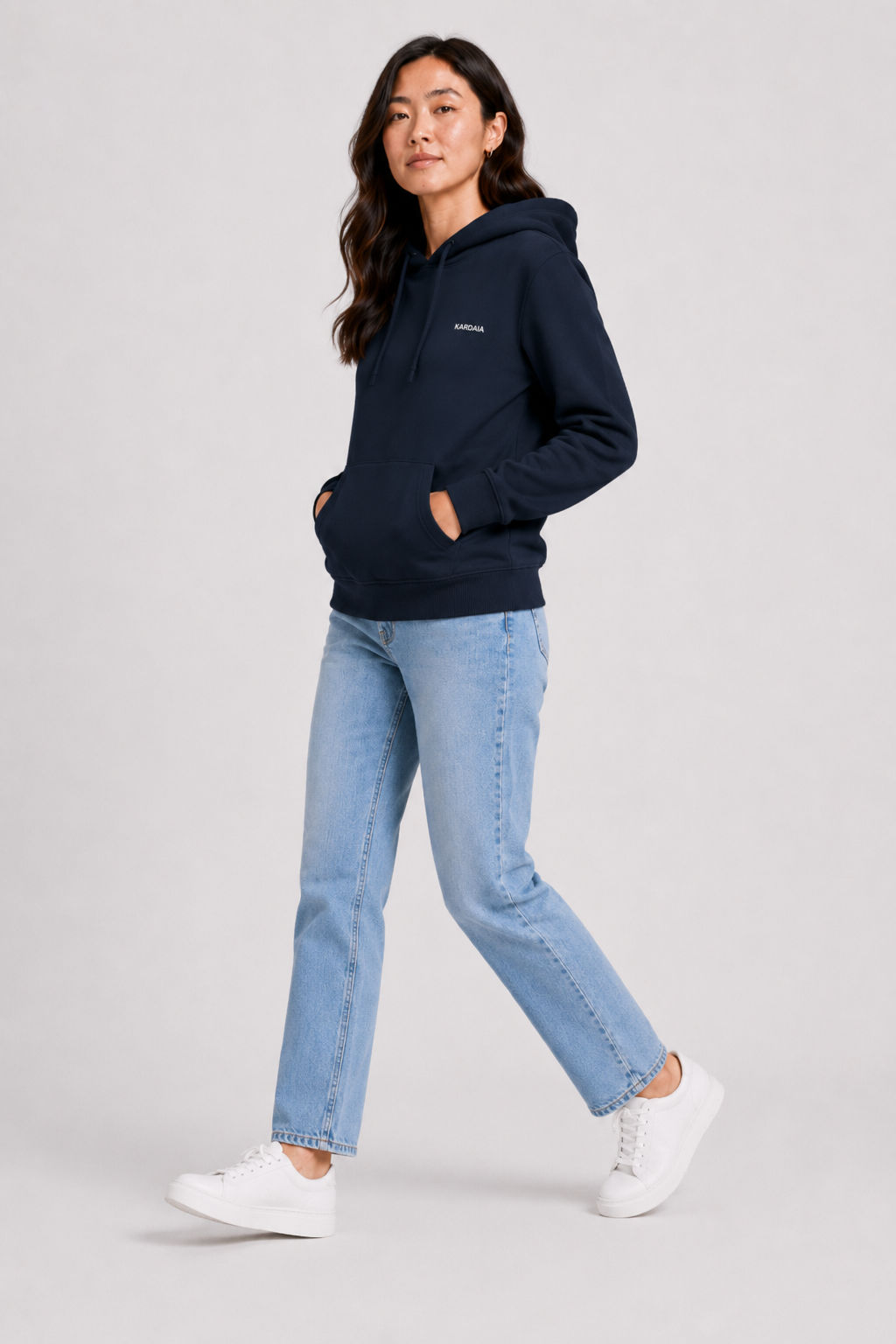 Femme portant un sweat à capuche bleu marine en coton biologique avec poche kangourou et jean clair