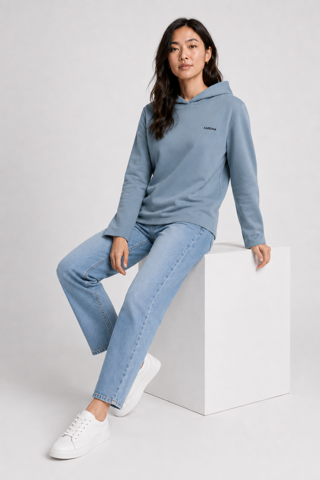 Femme portant un sweat à capuche bleu pierre en coton biologique avec un jean clair