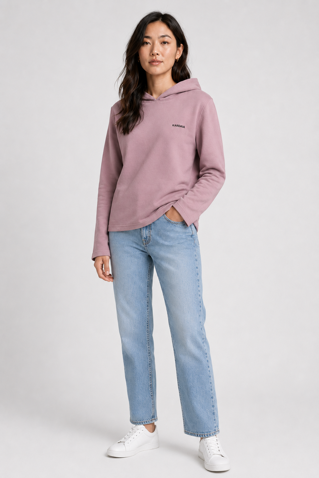 Femme portant un sweat à capuche mauve poudré en coton biologique avec un jean clair