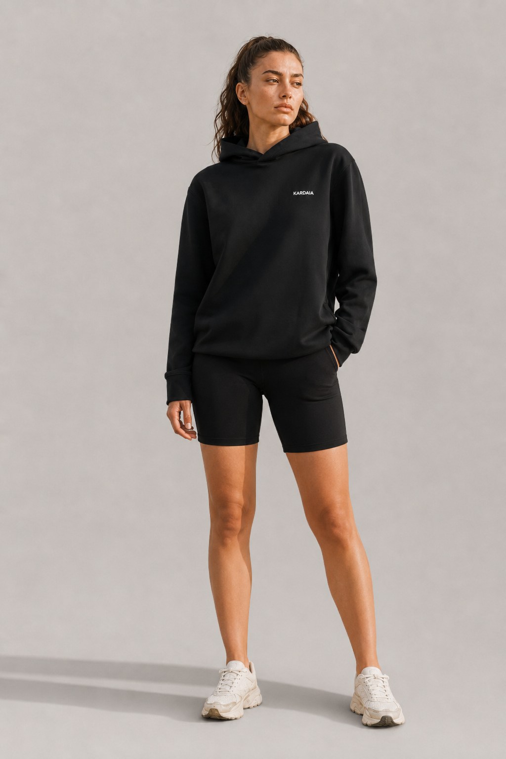 Sweat à capuche noir pour femme en coton biologique porté avec un short noir