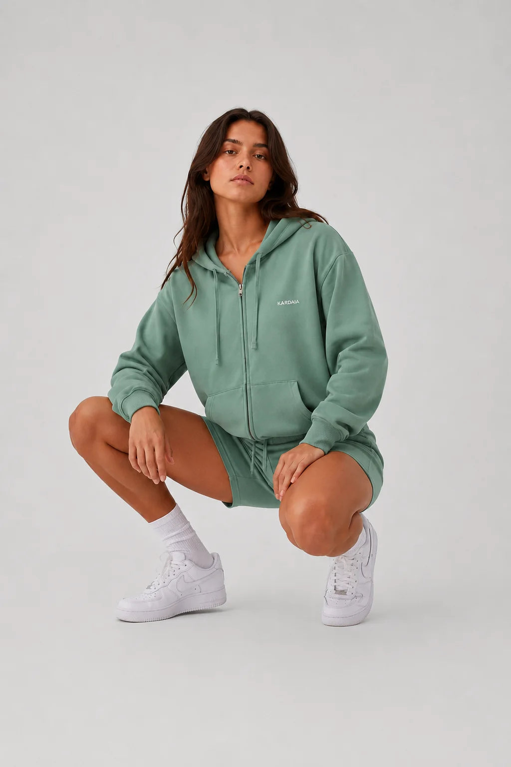 Sweat à capuche femme vert argile en coton bio porté accroupie