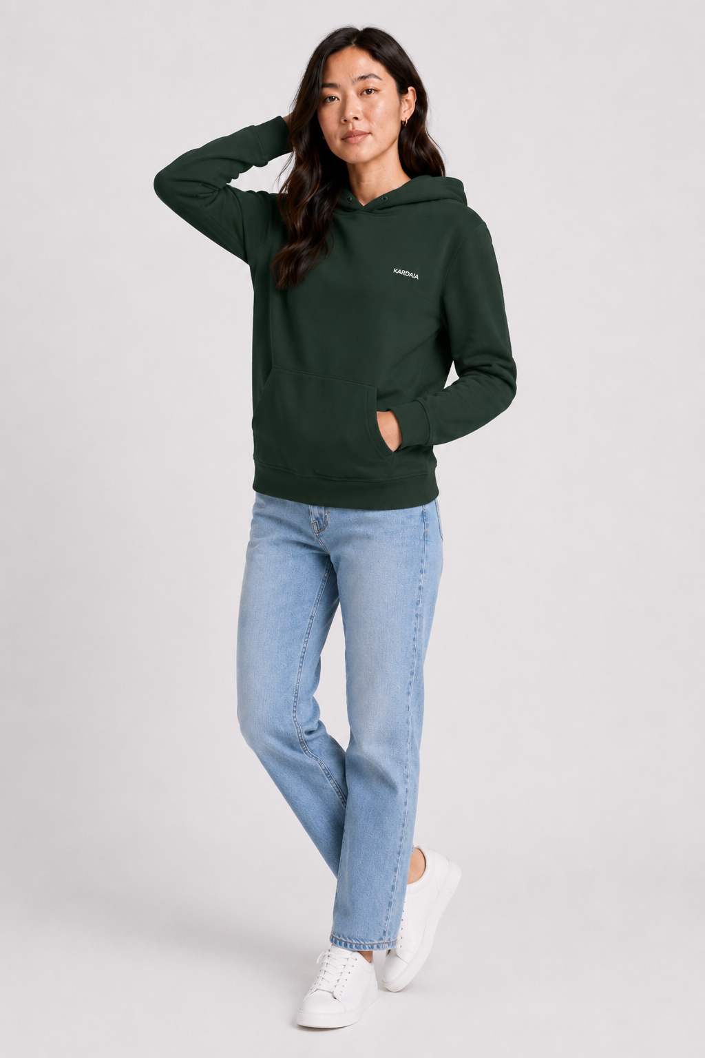 Femme portant un sweat à capuche kaki naturel en coton biologique avec poche kangourou et jean bleu