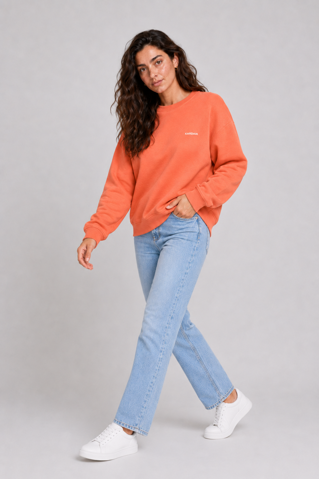 Femme portant un pull oversize orange en coton biologique avec un jean bleu