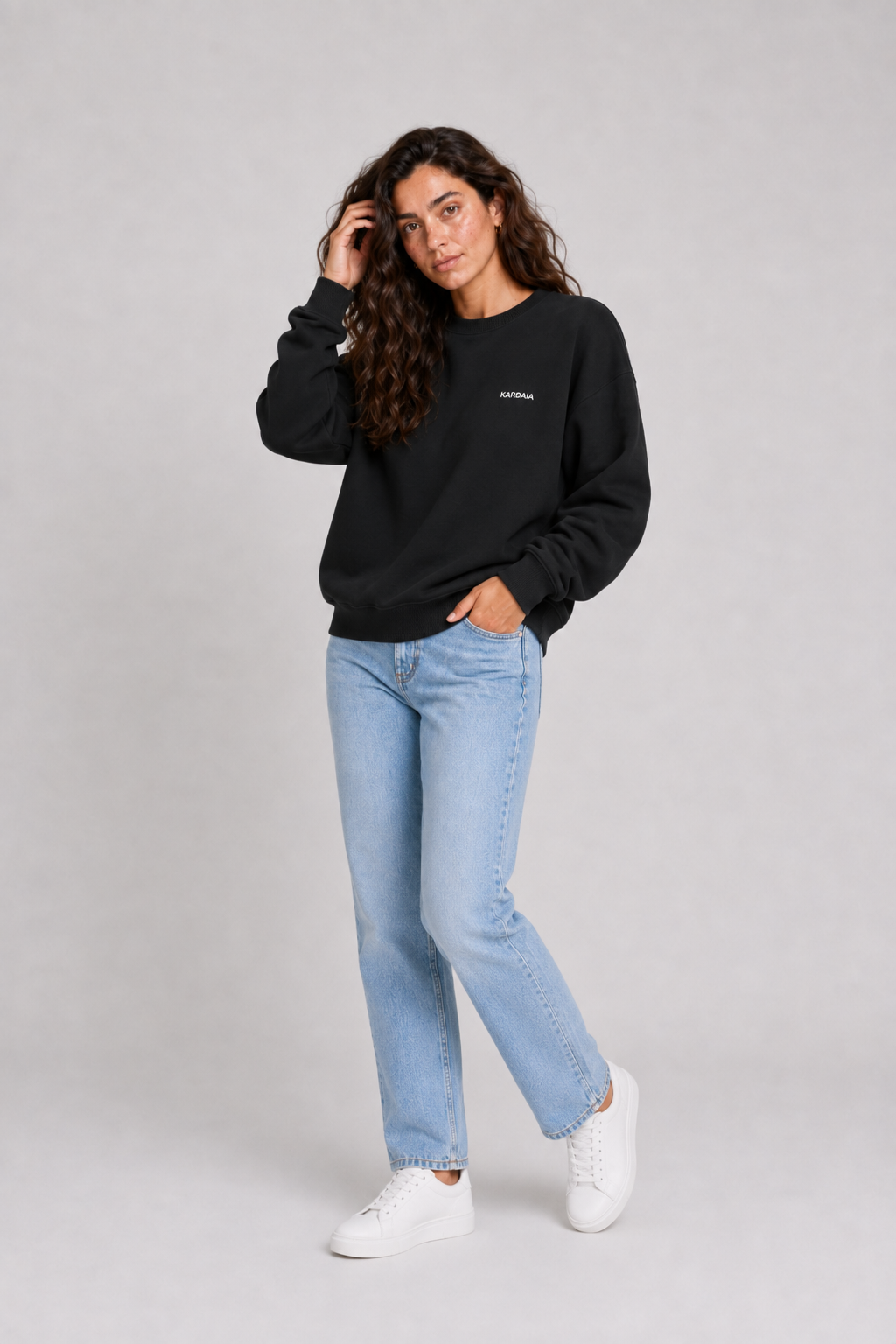 Pull oversize noir pour femme en coton biologique porté avec un jean bleu