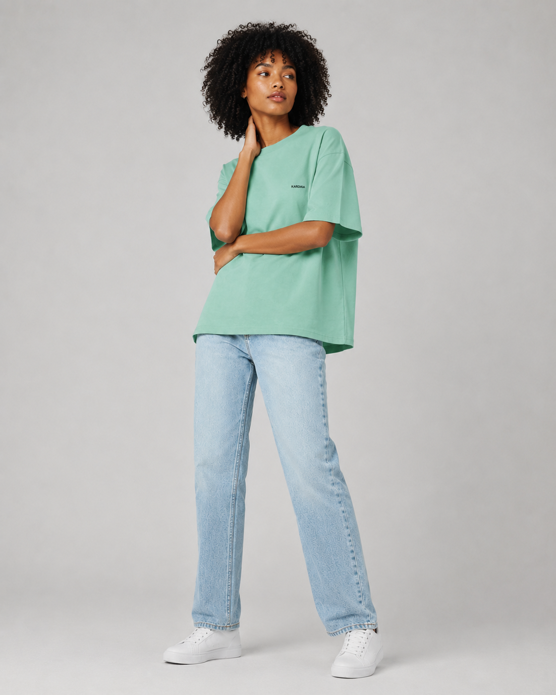 T-shirt vert menthe oversize pour femme en coton biologique porté assise avec un jean clair