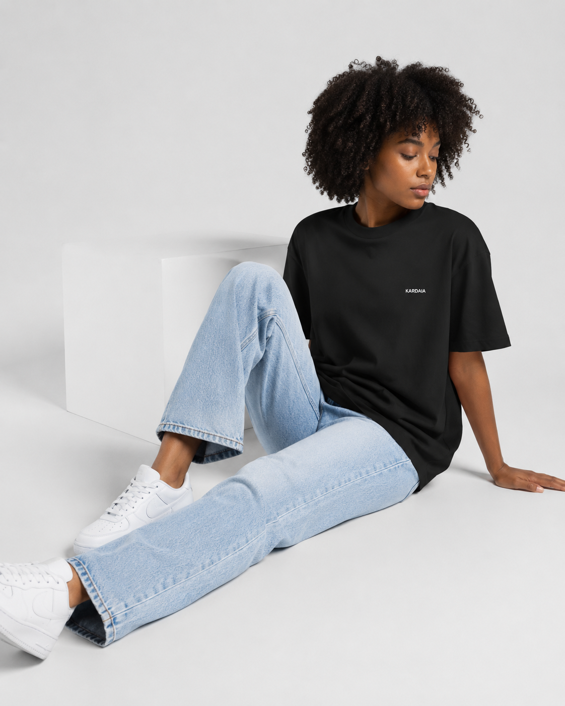 Femme assise portant un t-shirt oversize noir en coton biologique avec un jean bleu