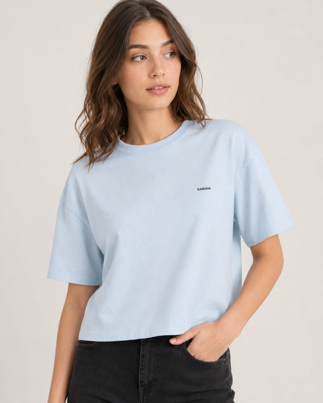 Gros plan sur un t-shirt boxy femme bleu clair en coton biologique porté avec un jean noir