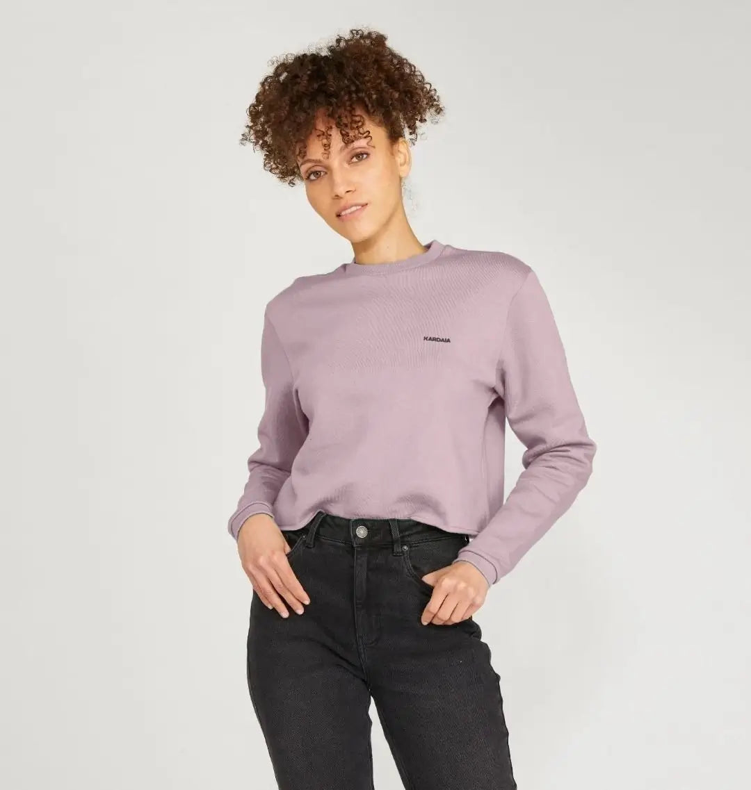 Femme portant un pull boxy mauve clair KARDAIA en coton bio, vue de face, mains dans les poches du jean noir