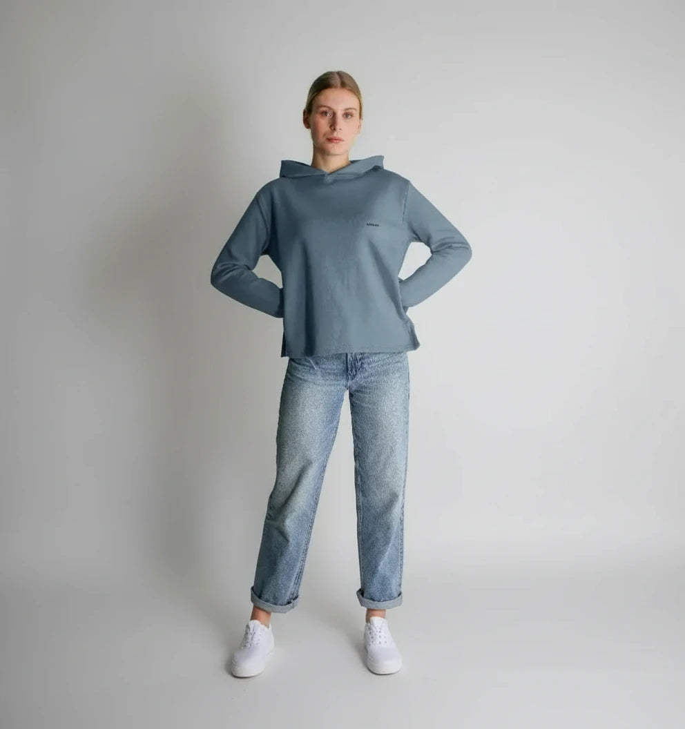 femme debout portant un sweat à capuche coupe décontractée couleur bleu pierre avec jean et baskets blanches