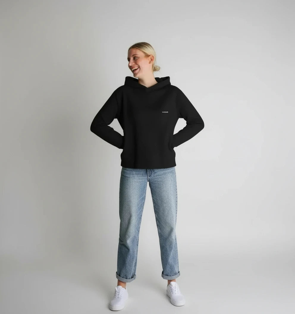 femme souriante portant un sweat à capuche noir coupe décontractée avec jean clair
