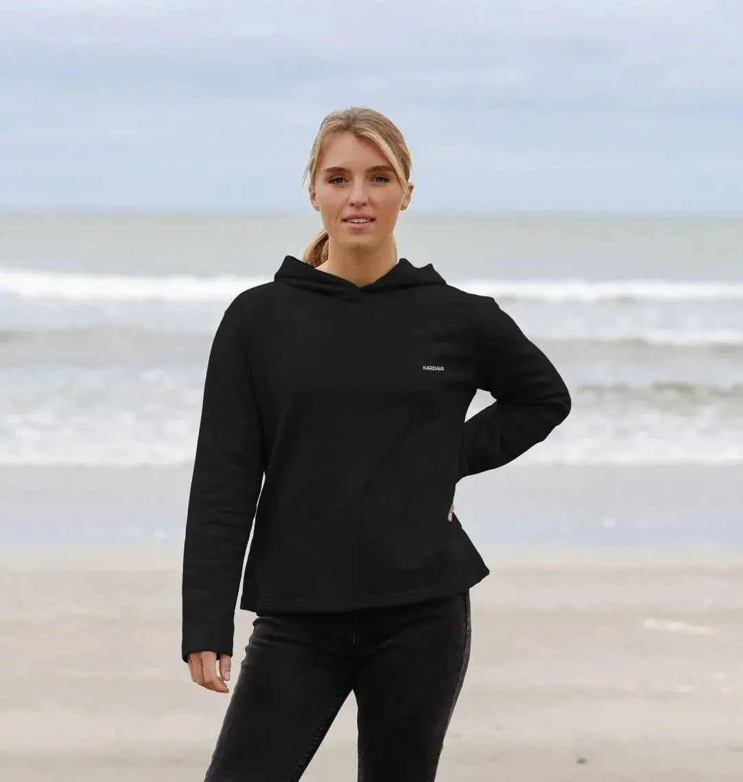 femme portant un sweat à capuche noir basalte sur la plage, coupe décontractée KARDAIA