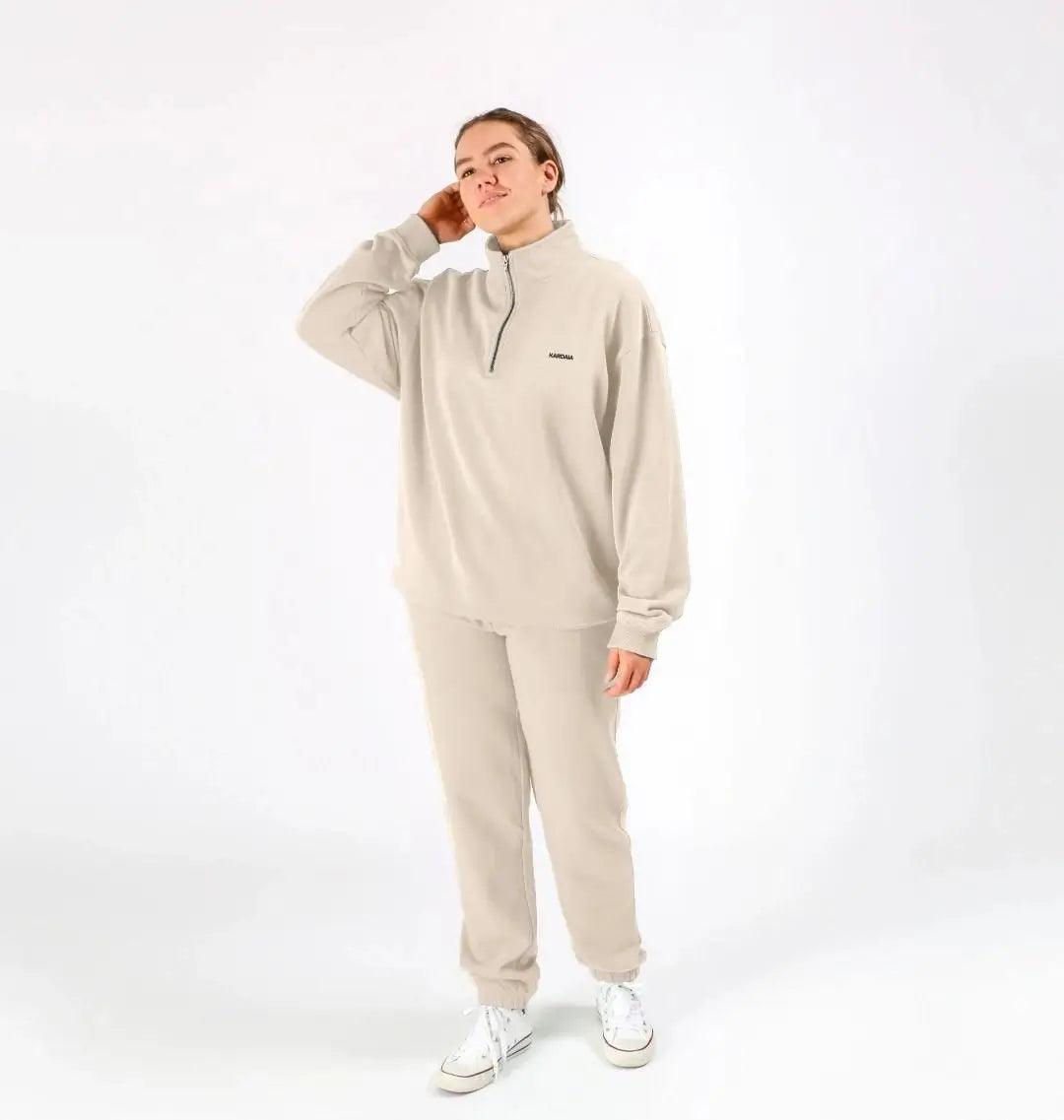 femme portant un sweat à col zippé couleur sable doux avec pantalon assorti et baskets blanches