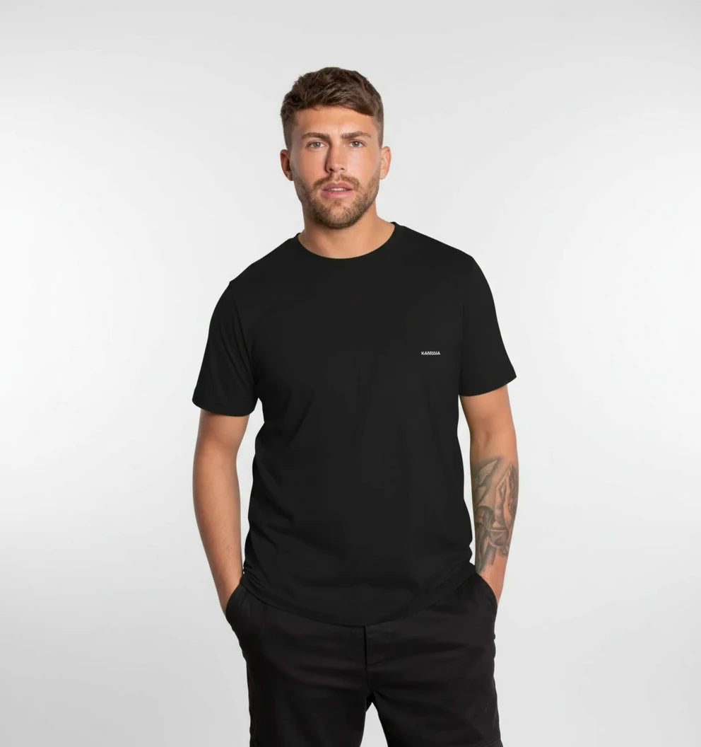 t-shirt basic noir KARDAIA porté par un homme devant un mur en briques de verre