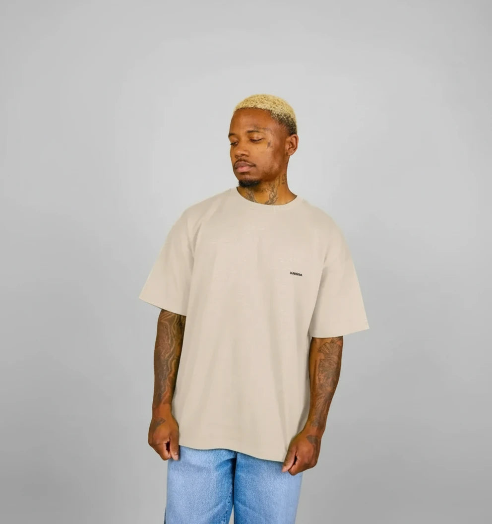 t-shirt oversize beige KARDAIA porté par un homme debout devant fond sable